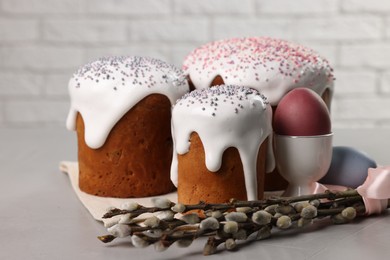 Photo of Tasty Easter cakes, decorated eggs and willow branches on grey table