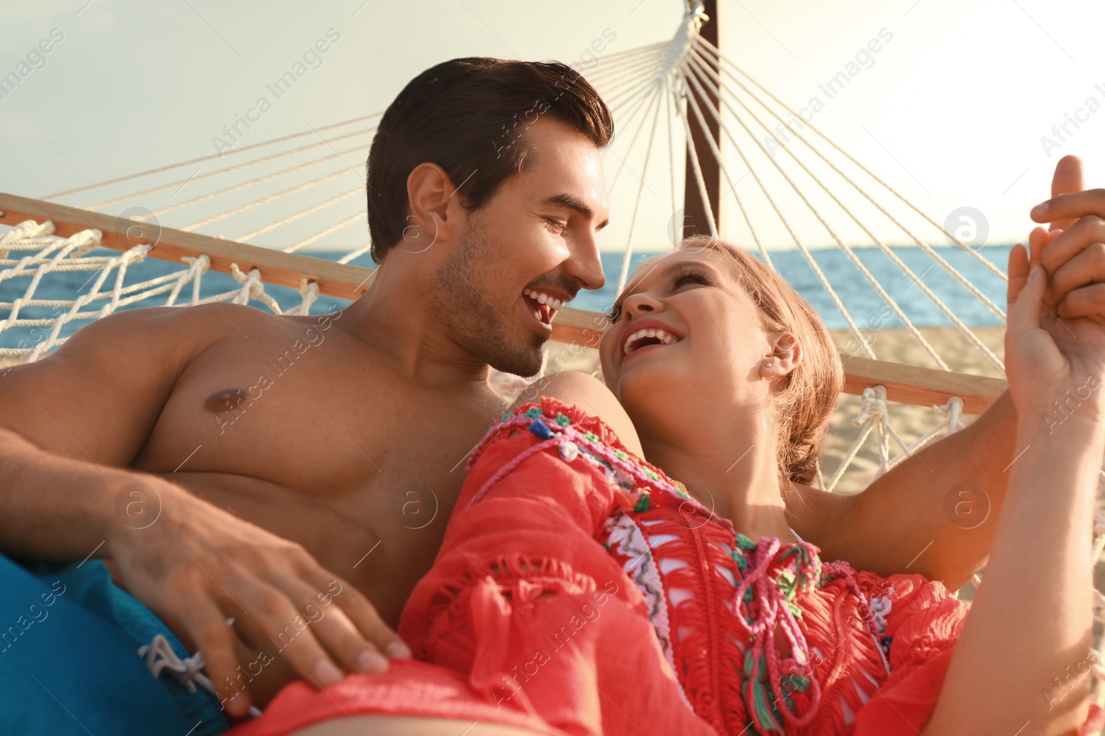 Photo of Beautiful young couple resting in hammock at sea beach