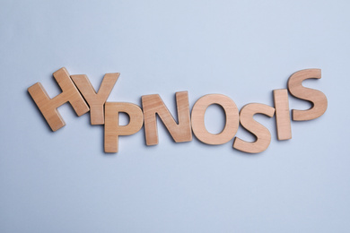 Photo of Word HYPNOSIS made with wooden letters on light background, flat lay