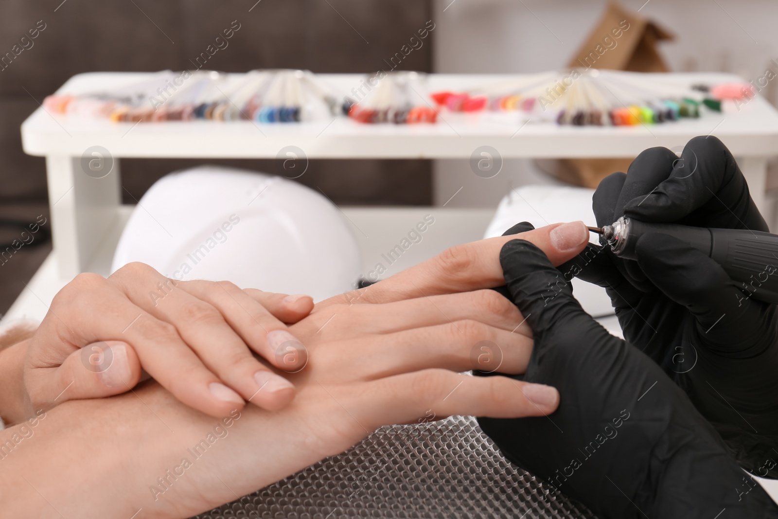 Photo of Professional manicurist working with client in salon, closeup