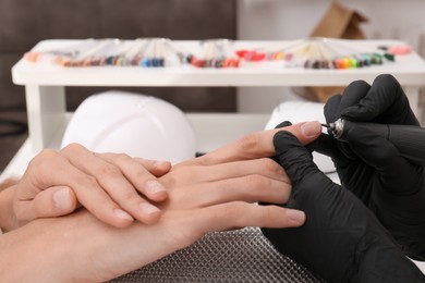 Professional manicurist working with client in salon, closeup
