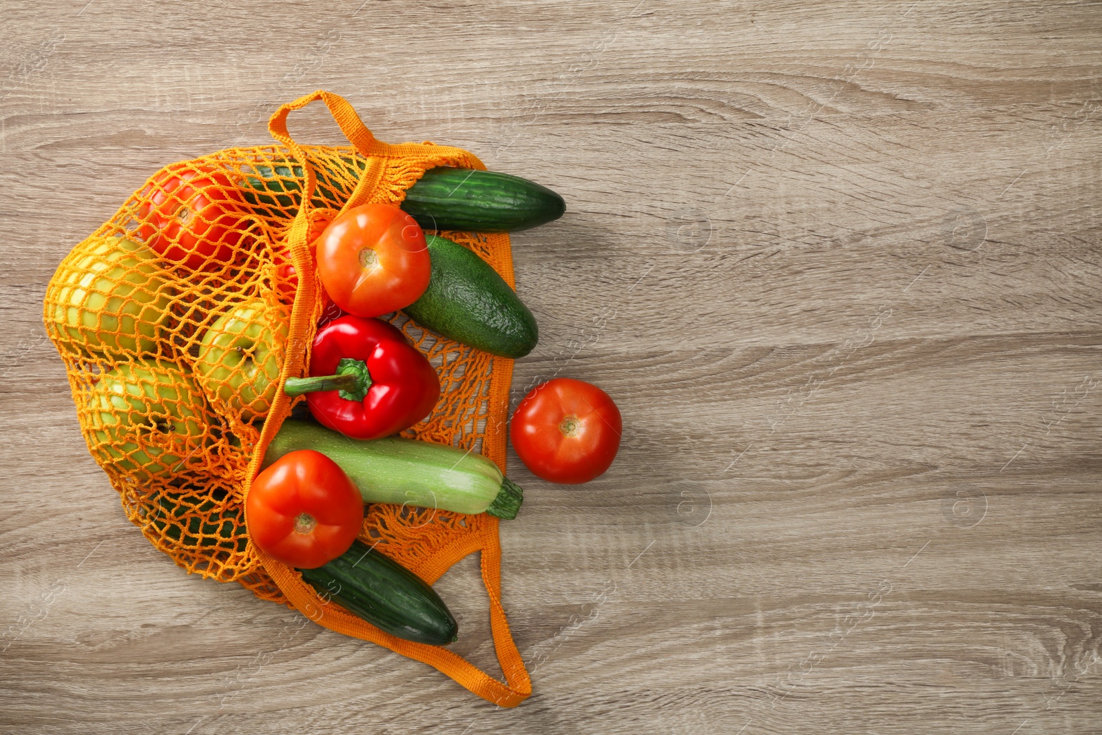 Photo of Net bag with vegetables and fruits on wooden table, top view. Space for text