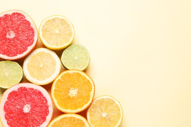 Photo of Different cut citrus fruits on beige table, flat lay. Space for text