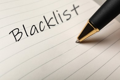 Writing word Blacklist with pen in notepad, closeup