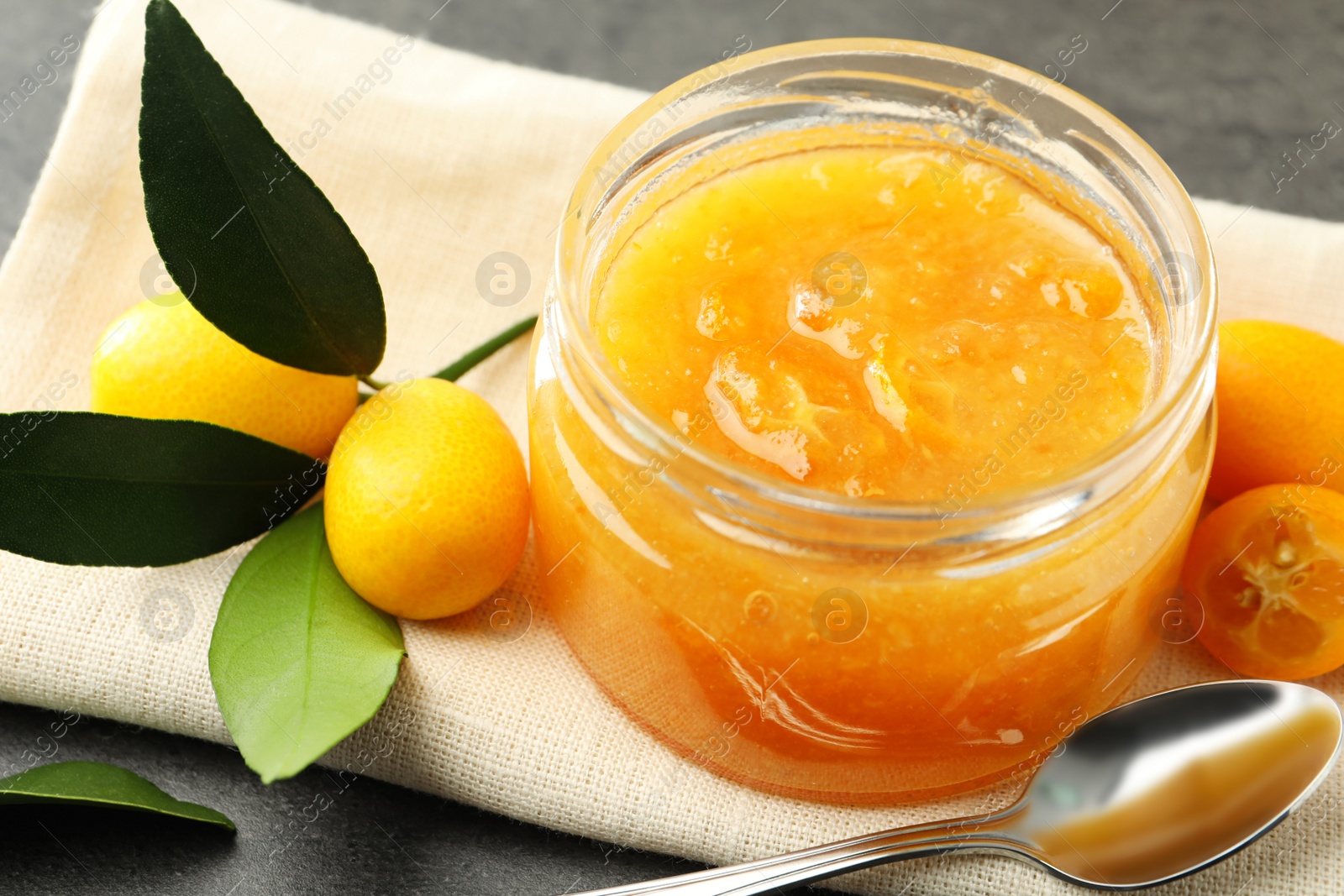 Photo of Delicious kumquat jam and fresh fruits on table, closeup