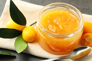 Delicious kumquat jam and fresh fruits on table, closeup
