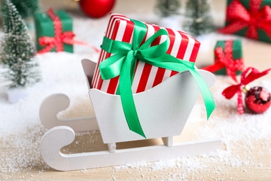 Photo of Sleigh with gift box on wooden table