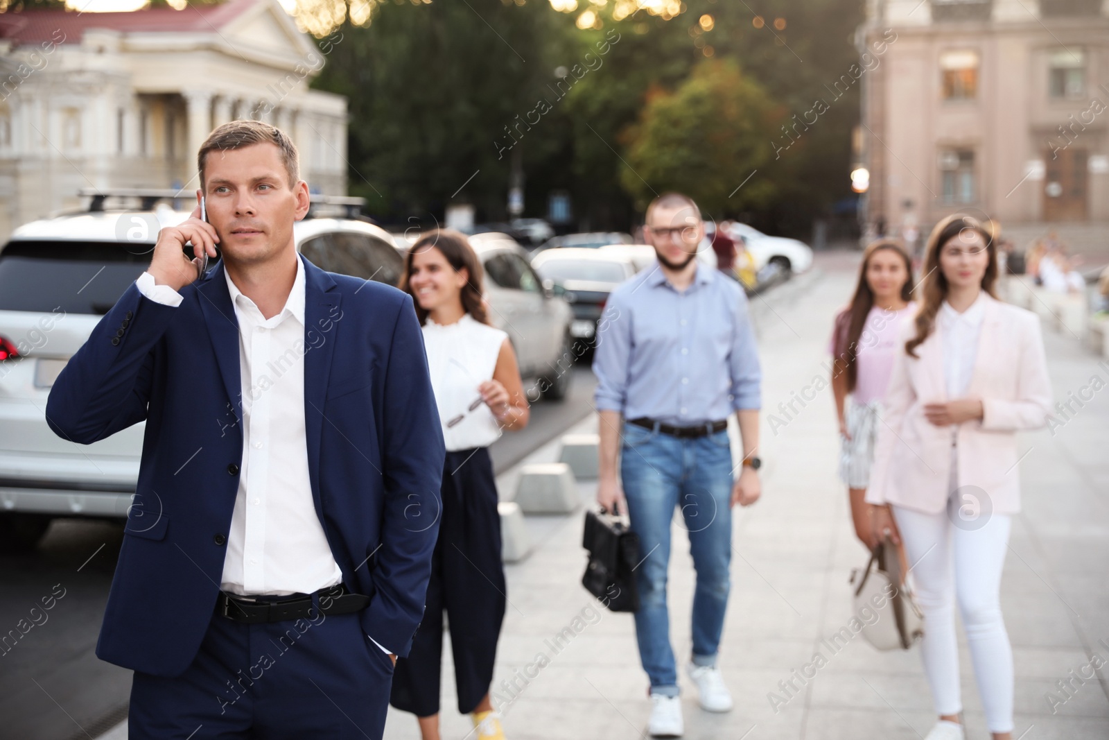 Photo of Businessman talking on phone while walking city street