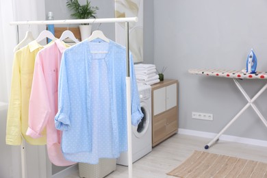 Photo of Laundry room interior with washing machine and clothes on rack