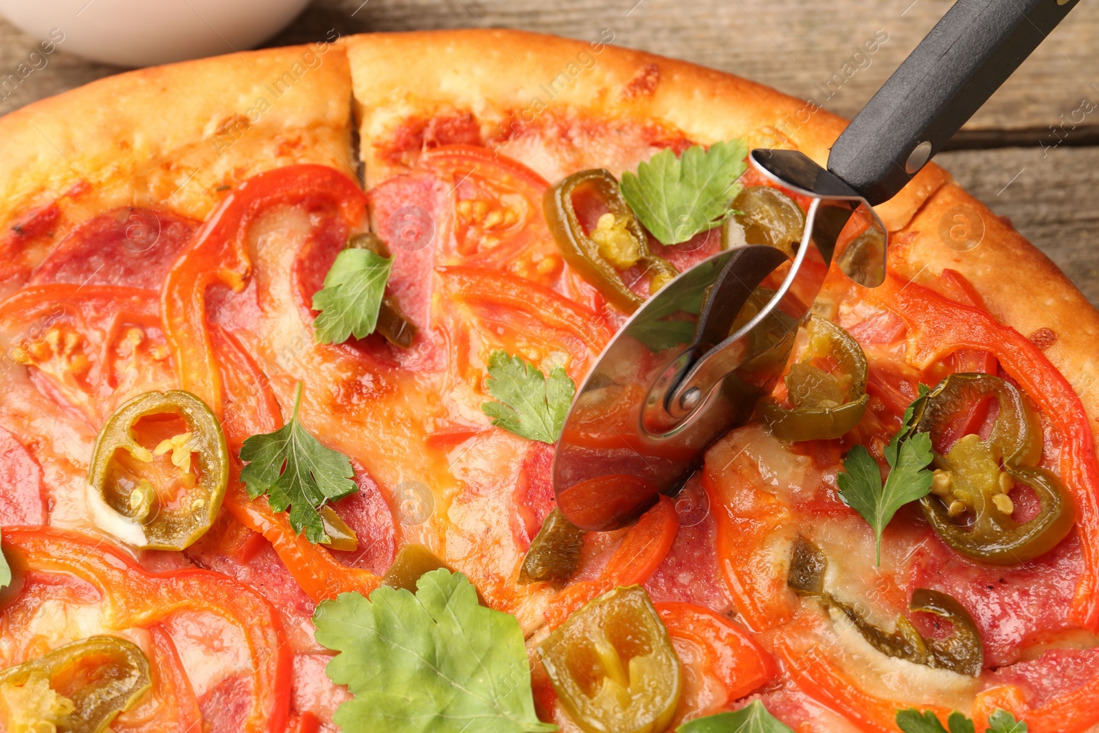 Photo of Cutting delicious pizza Diablo at table, closeup