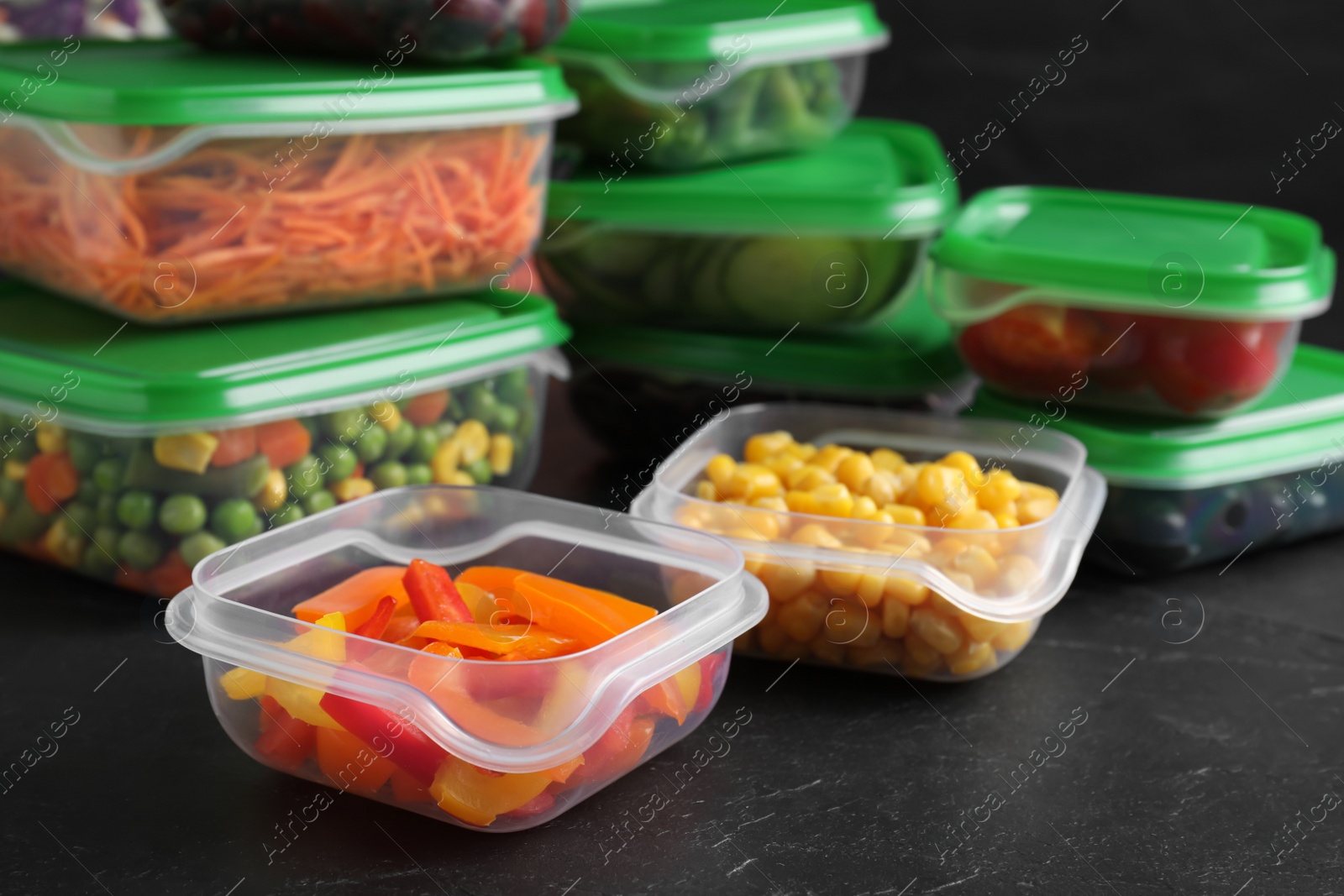 Photo of Set of plastic containers with fresh food on black table