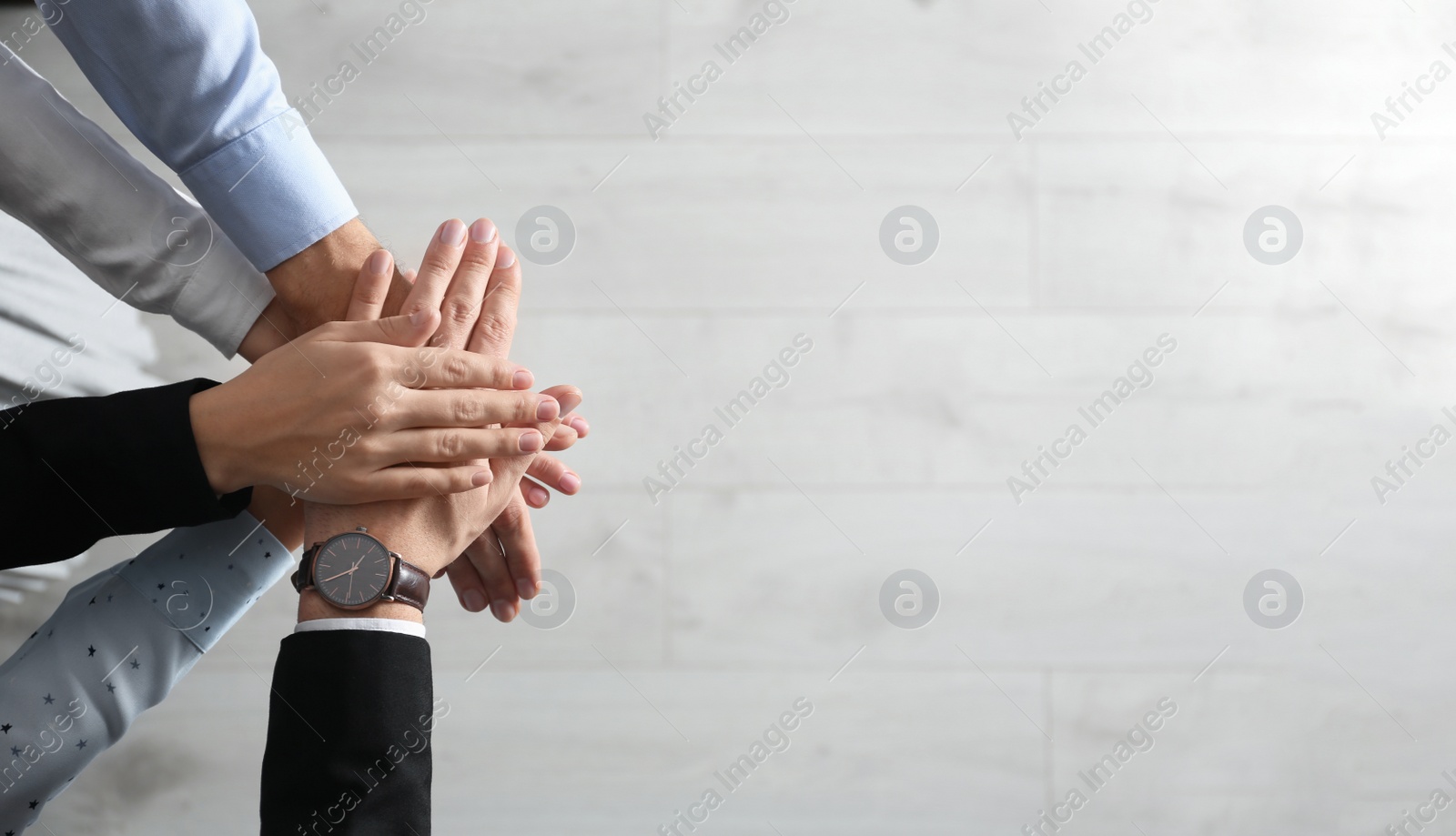 People holding hands together over light wooden background, top view with space for text. Unity concept Photo of People holding hands together over light wooden background, top view with space for text. Unity concept