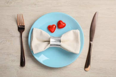 Photo of Beautiful table setting with heart shaped candies for romantic dinner on white wooden table, flat lay