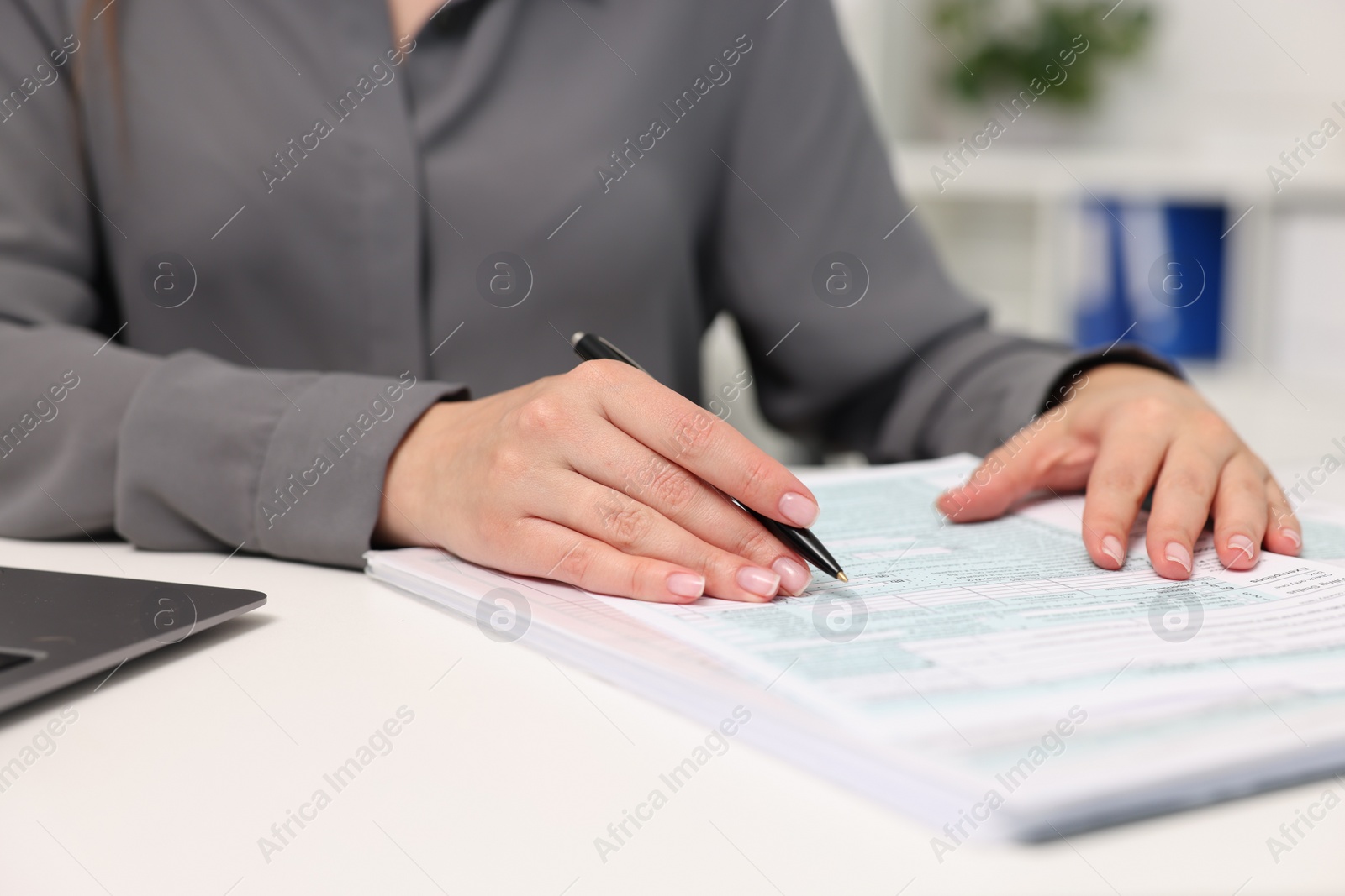 Photo of Secretary doing paperwork at table in office, closeup