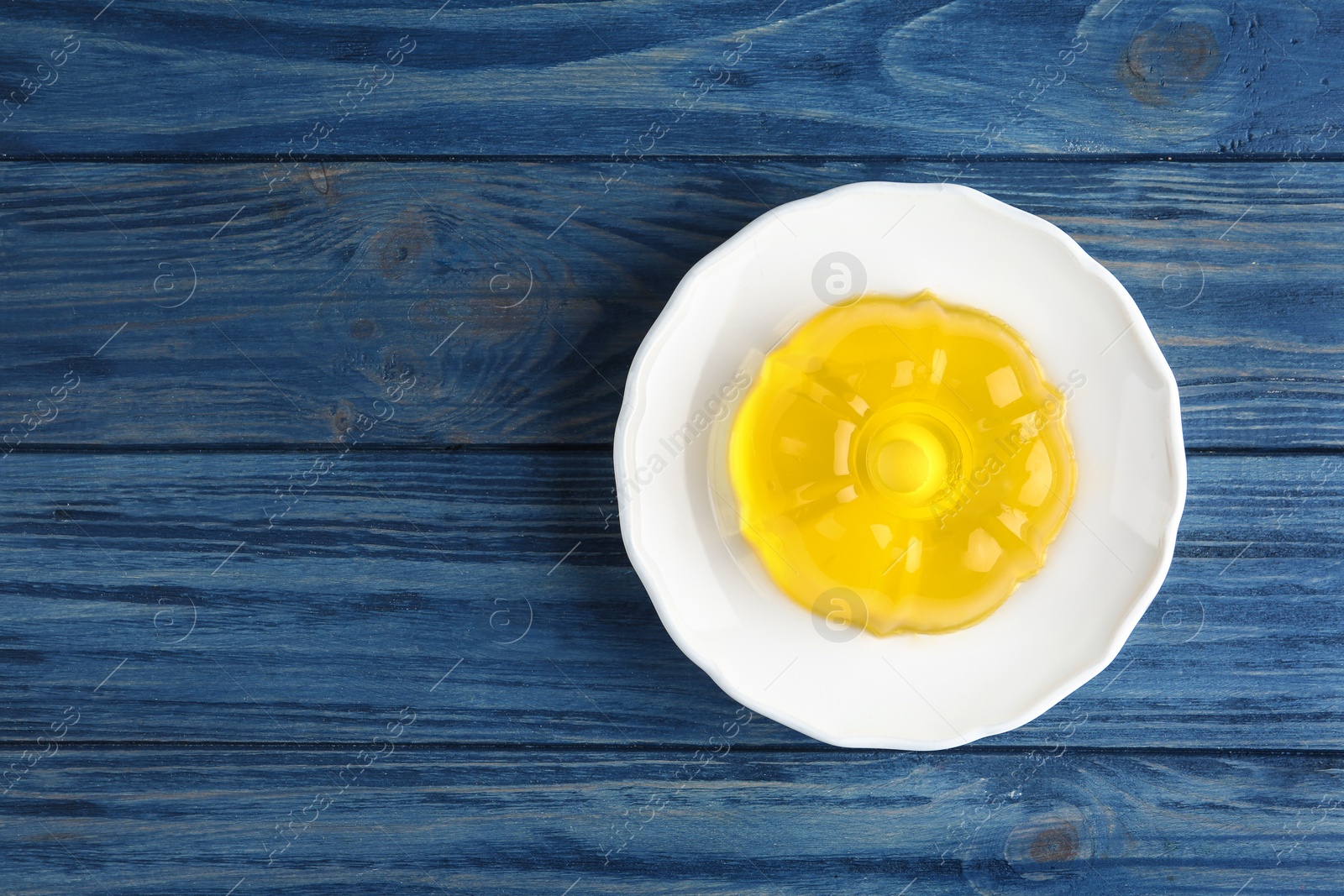 Photo of Plate with tasty fruit jelly on blue wooden table, top view. Space for text