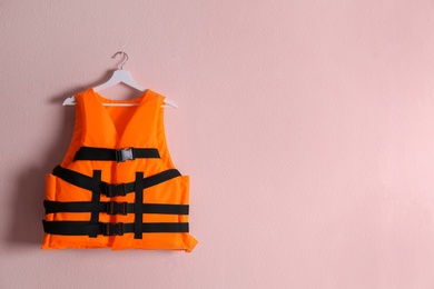 Photo of Orange life jacket on pink background. Space for text