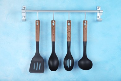 Rack with kitchen utensils hanging on light blue wall