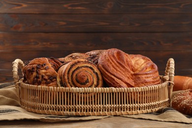 Wicker basket with different tasty freshly baked pastries on table