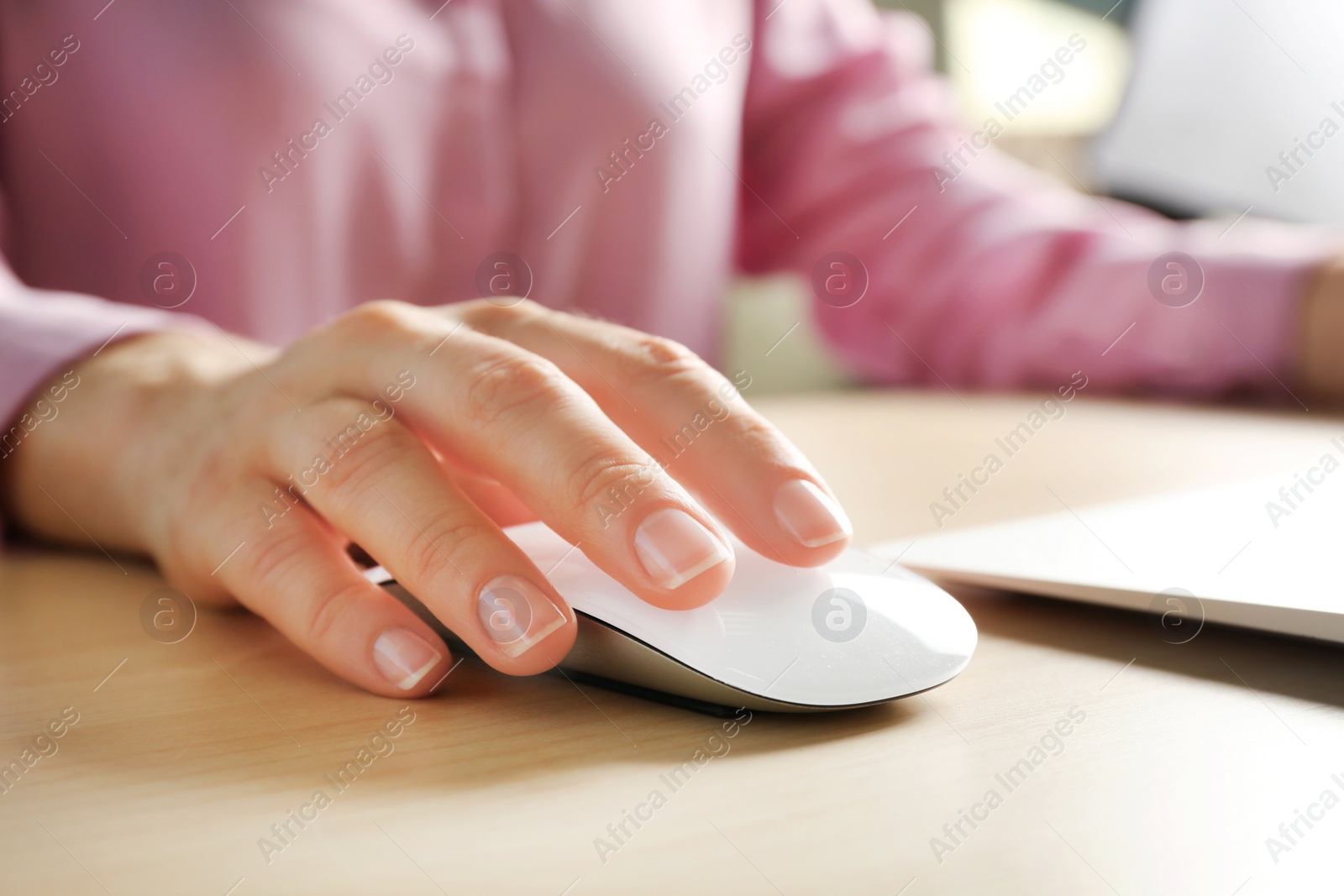 Photo of Woman using computer mouse with laptop at table, closeup