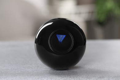 Photo of Magic eight ball with prediction Looks Like Yes on light gray table, closeup