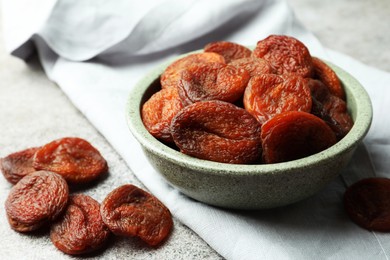 Photo of Bowl of tasty apricots on grey table, closeup. Dried fruits