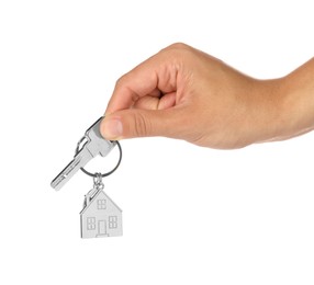 Woman holding key with metallic keychain in shape of house on white background, closeup