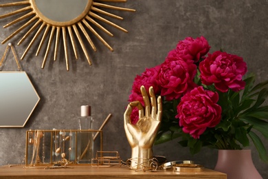 Photo of Composition with gold accessories and flowers on dressing table near grey wall