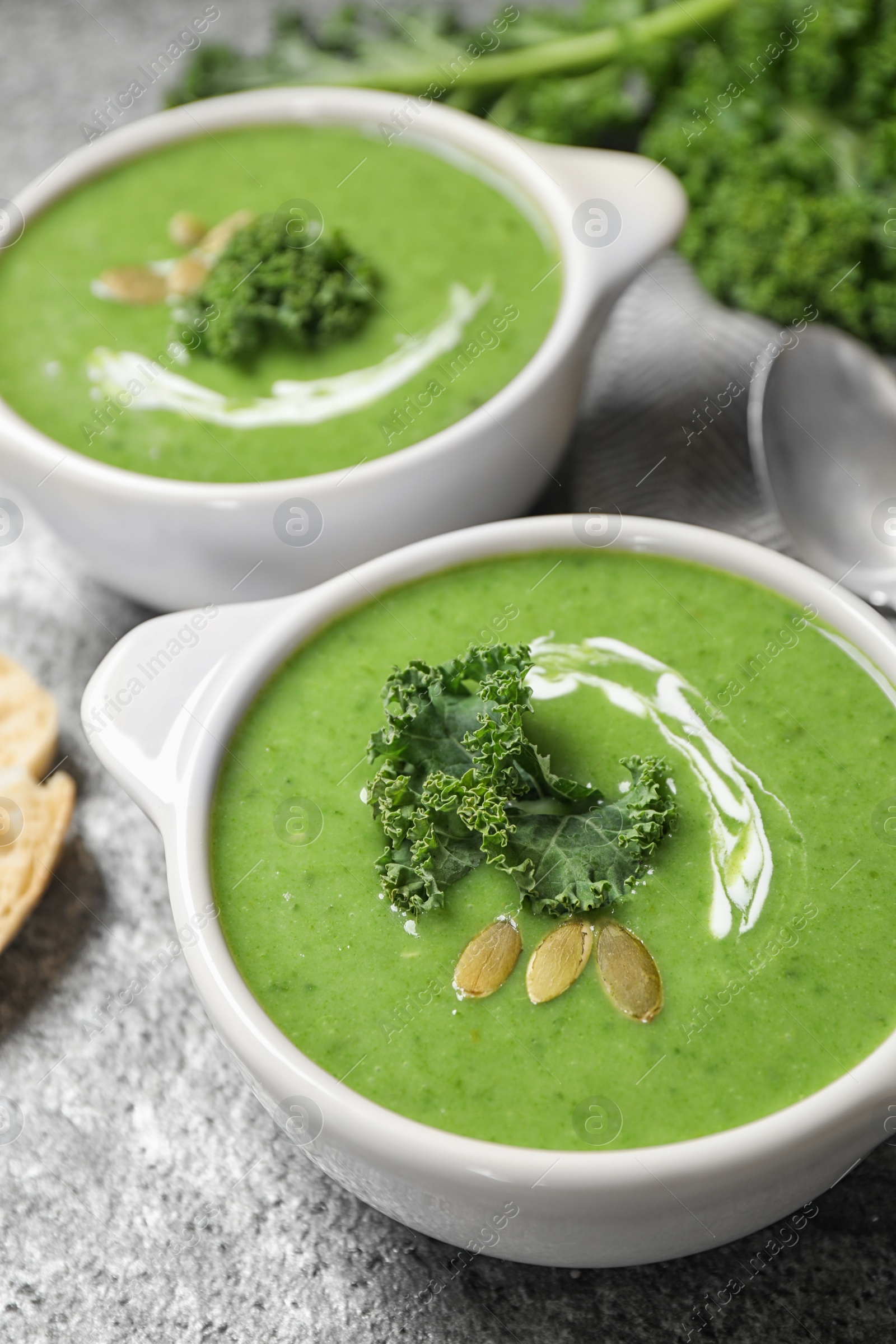 Photo of Tasty kale soup with pumpkin seeds on grey table