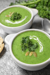 Photo of Tasty kale soup with pumpkin seeds on grey table