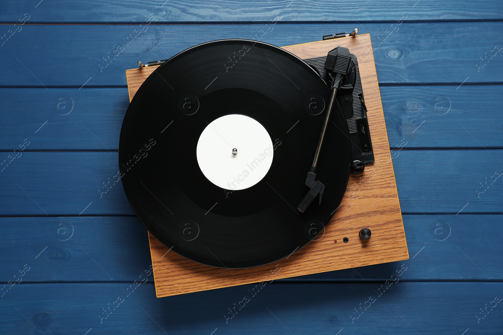 Photo of Turntable with vinyl record on blue wooden background, top view