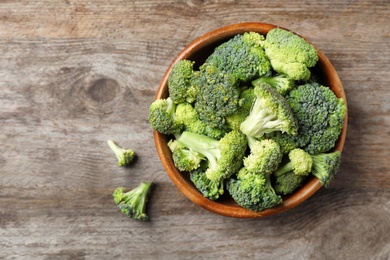 Photo of Bowl with fresh green broccoli on wooden background, top view