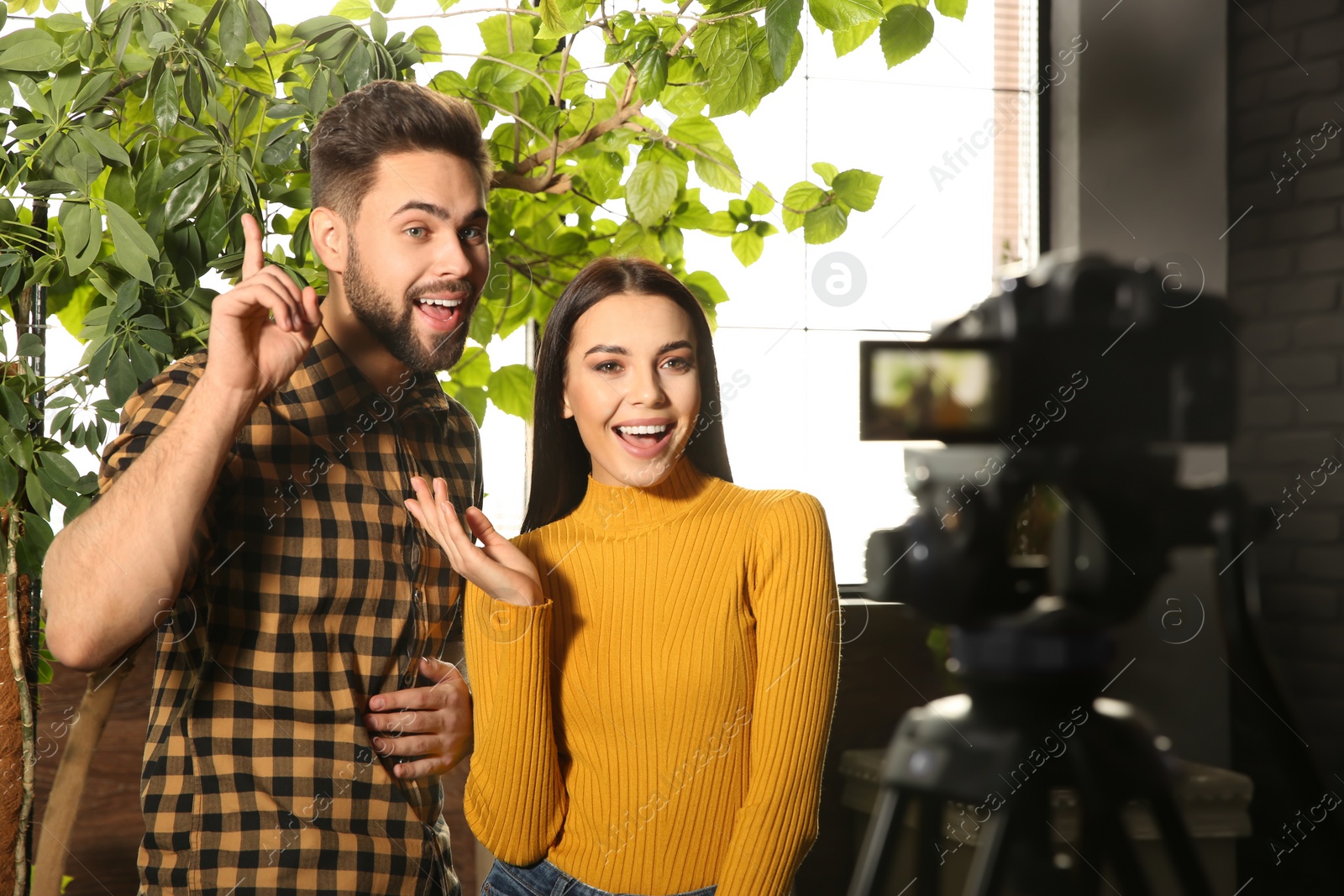 Photo of Young bloggers recording video on camera indoors