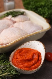 Photo of Marinade, raw chicken and rosemary on brown table, closeup