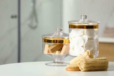 Composition of glass jar with cotton pads on table in bathroom. Space for text