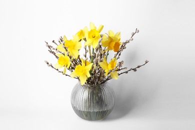 Photo of Bouquet of beautiful yellow daffodils and willow twigs in vase on white background