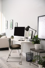 Photo of Comfortable workplace with modern computer and houseplants in room. Interior design