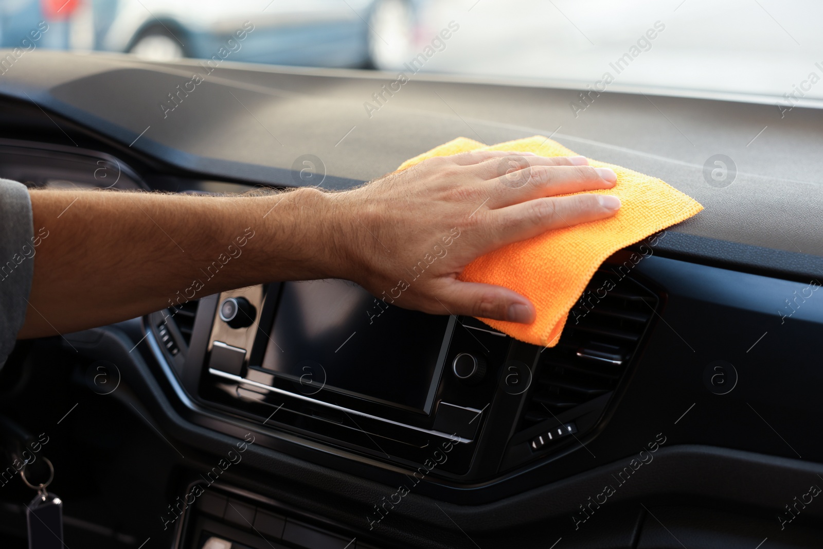 Photo of Man cleaning center console with rag in car, closeup