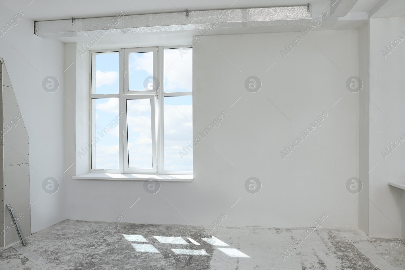 Photo of Empty room with white wall and windows prepared for renovation