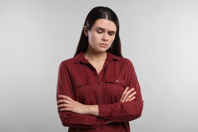 Photo of Sadness. Unhappy woman with crossed arms on gray background