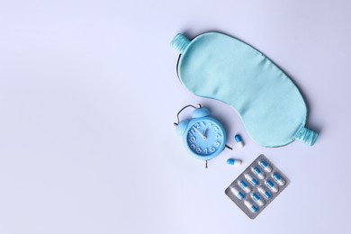 Sleeping mask, pills and alarm clock on white background, flat lay. Insomnia treatment