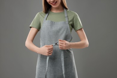 Photo of Woman wearing kitchen apron on grey background, closeup. Mockup for design