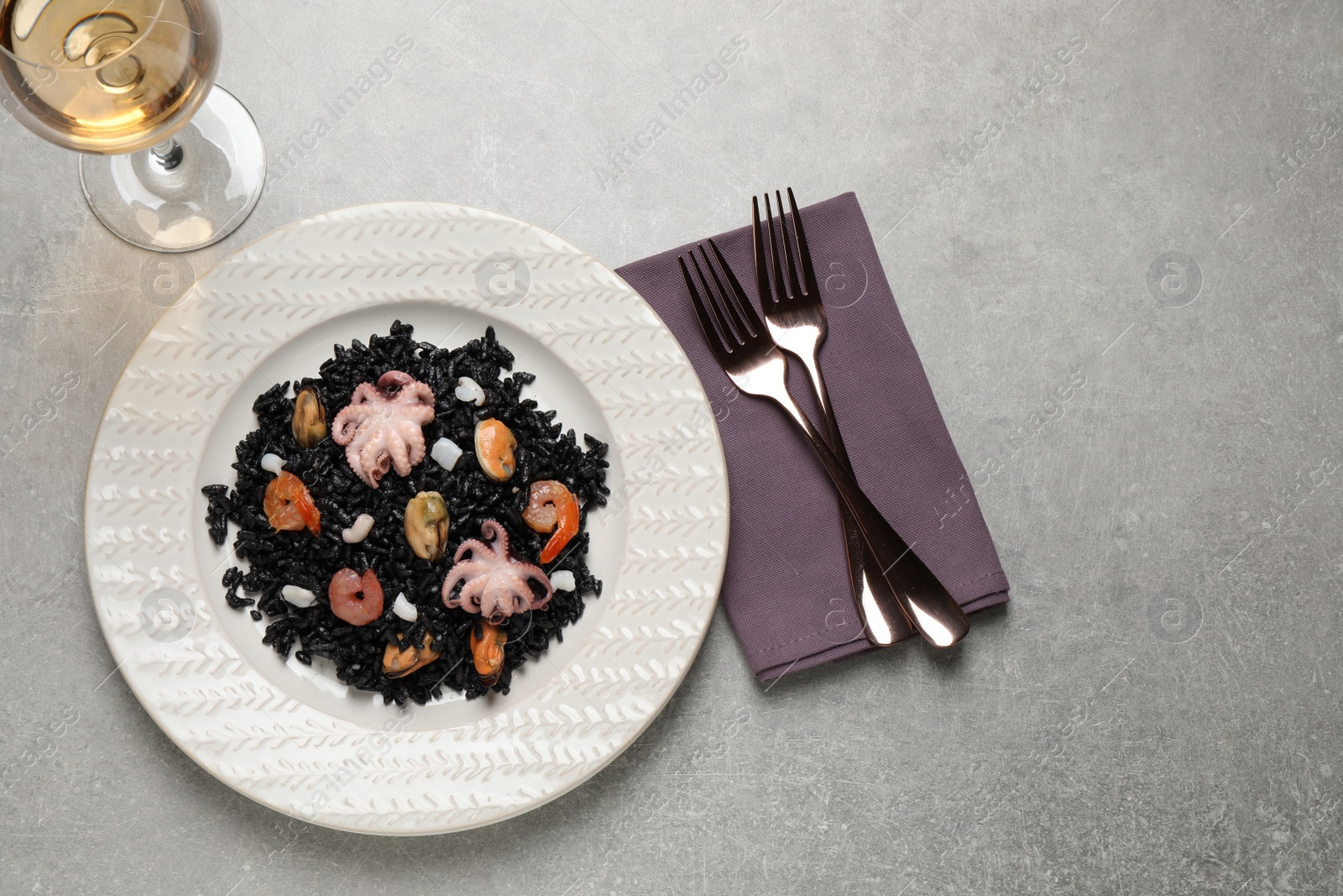 Photo of Delicious black risotto with seafood served on light grey table