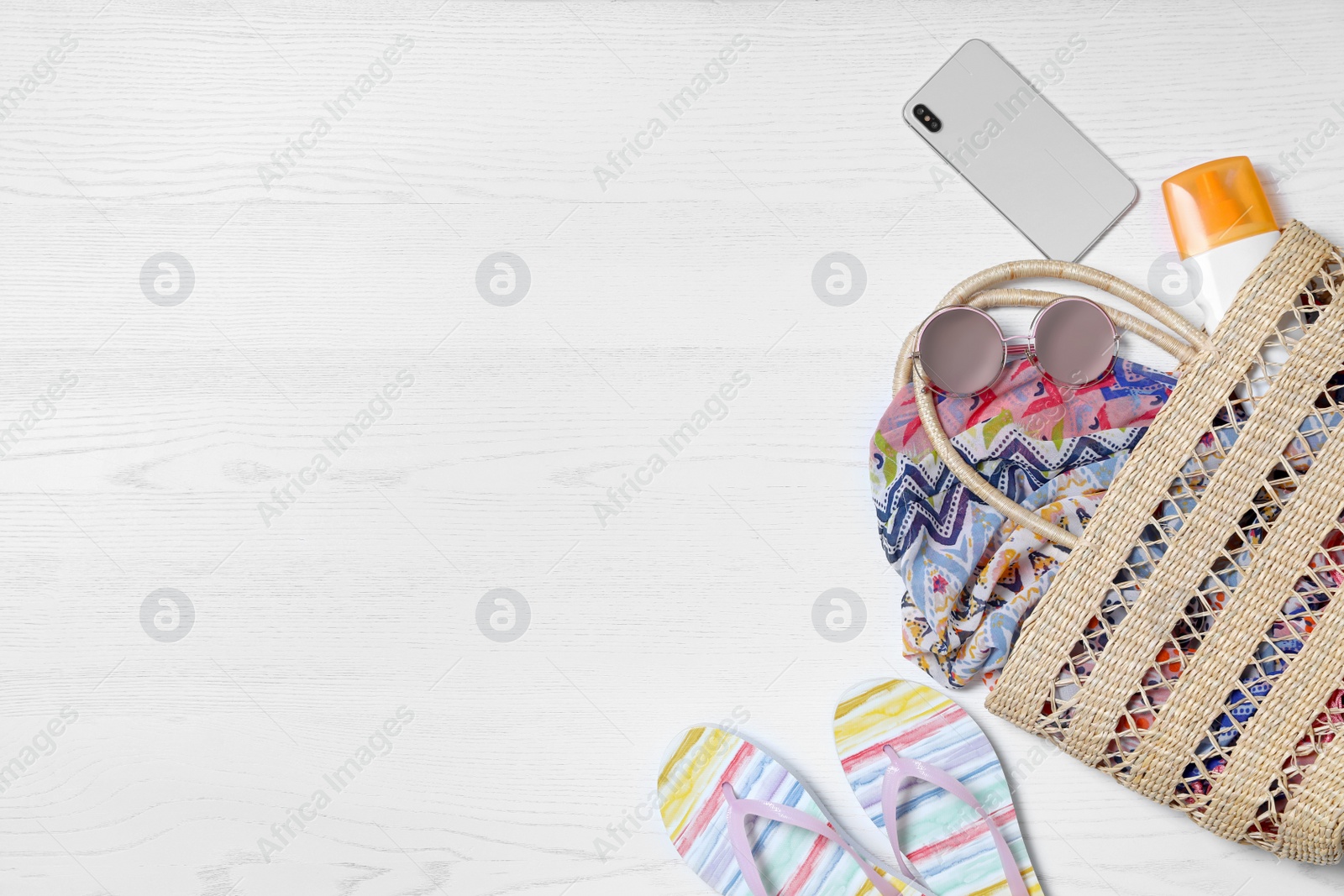 Photo of Flat lay composition with beach bag and accessories on white wooden background, space for text