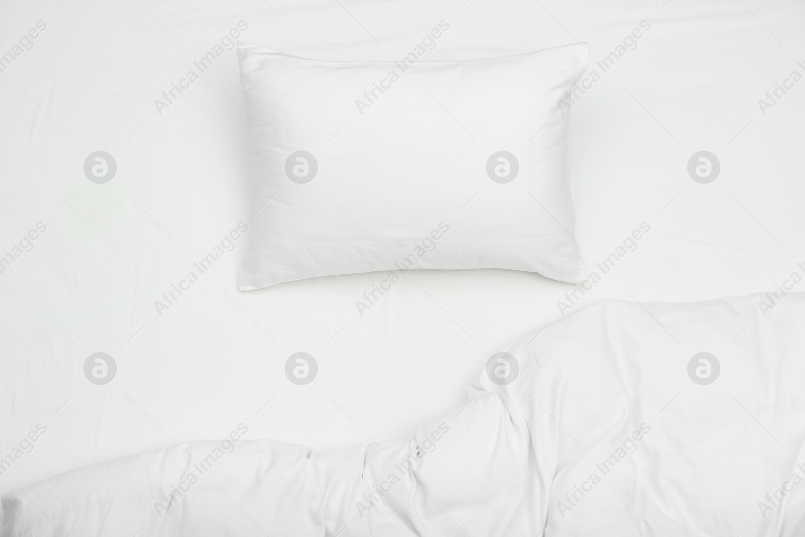 Photo of Soft white pillow and blanket on bed, top view