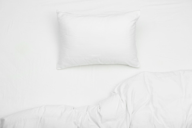 Photo of Soft white pillow and blanket on bed, top view