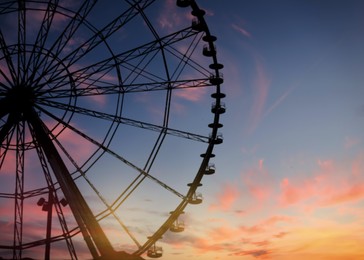 Image of Beautiful large Ferris wheel outdoors at sunset