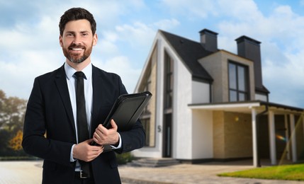 Smiling real estate agent with portfolio near beautiful house outdoors. Space for text