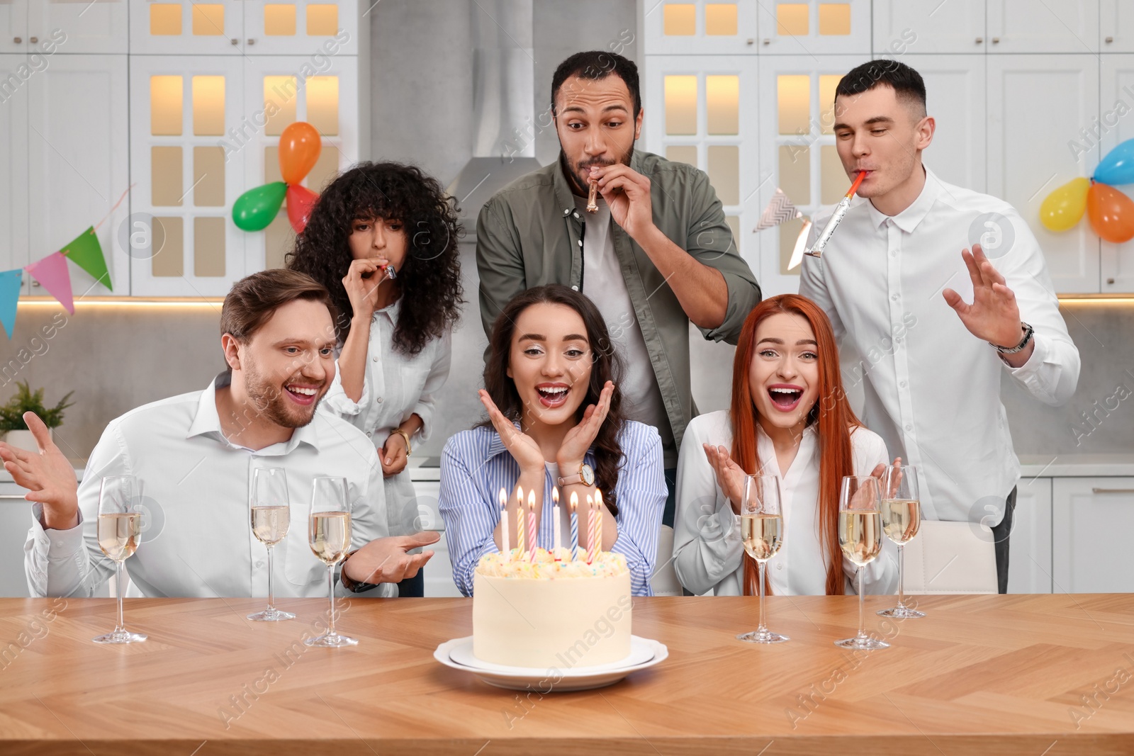 Photo of Happy friends with tasty cake celebrating birthday in kitchen