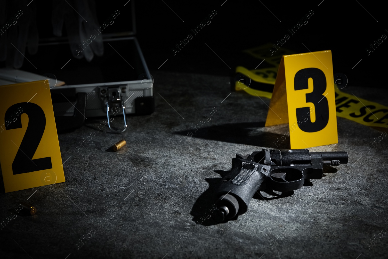 Photo of Shell casing, gun and crime scene marker on grey stone table