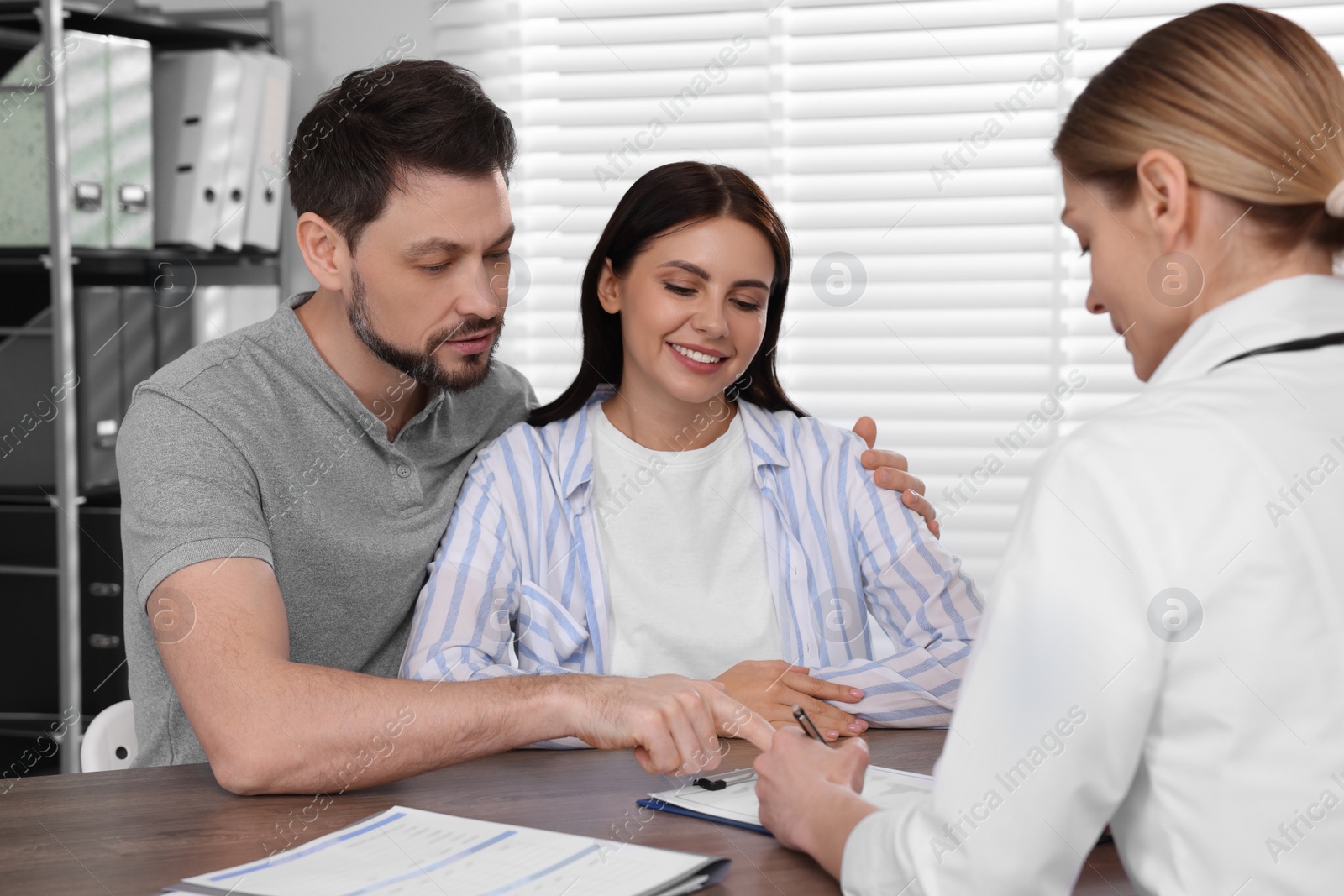 Photo of Couple having appointment with fertility doctor in clinic. Patient consultation